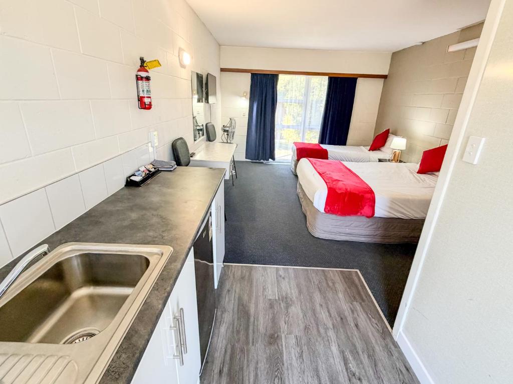 a bathroom with a sink and a bedroom with a bed at Midway Pacifica Lodge in Lower Hutt