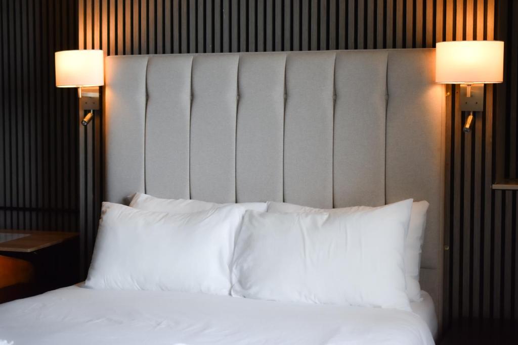 ein Bett mit weißen Kissen und zwei Lampen darauf in der Unterkunft Nomi Rooms & Restaurant in Bangor
