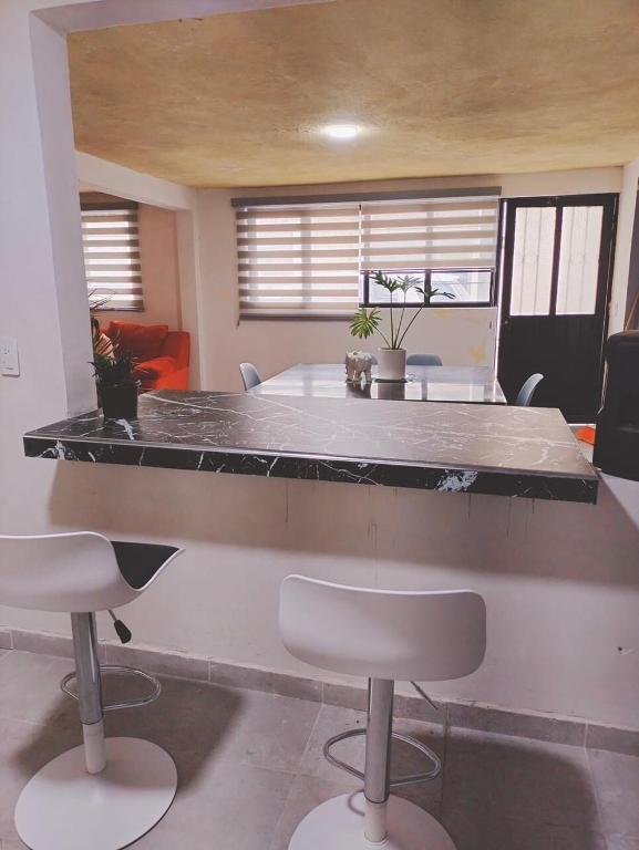 a kitchen with a large counter with two white chairs at Casa Altita Accommodation in Zacatlán