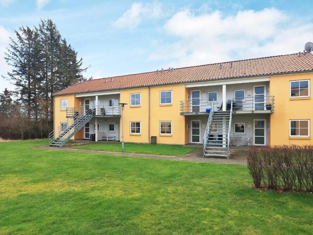a large yellow building with stairs in a yard at Hals Apartment 100m from Beach in Hals
