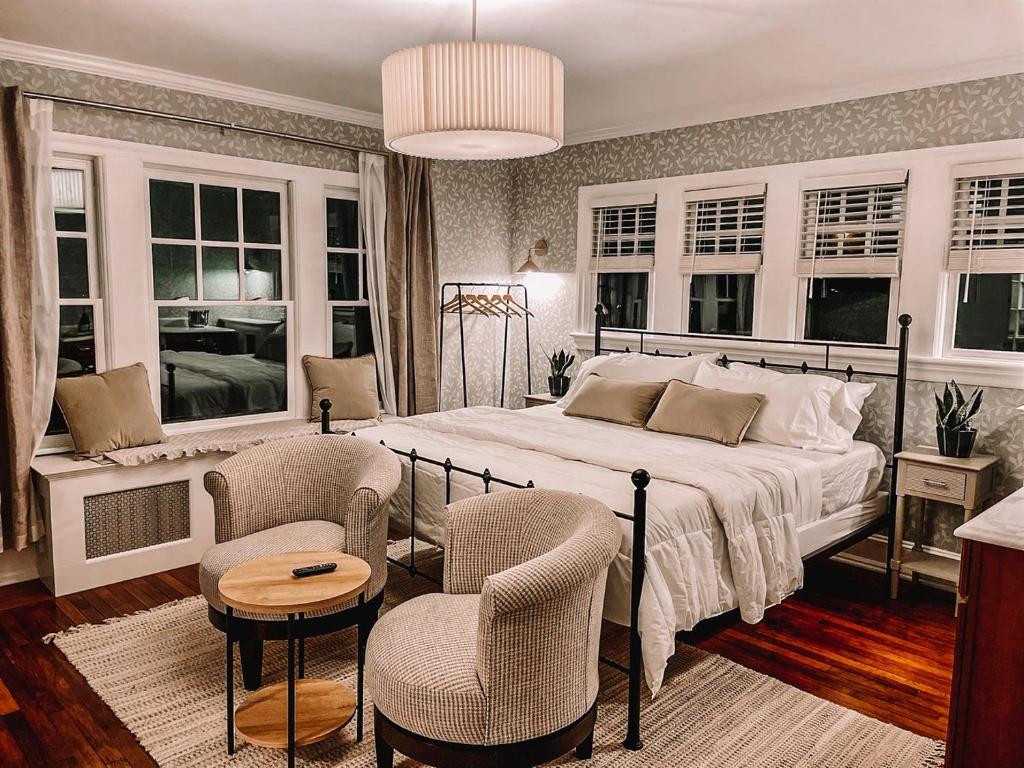 a bedroom with a bed and chairs and windows at Buttonwood Hotel 1 - Boutique Accommodations in Cape May