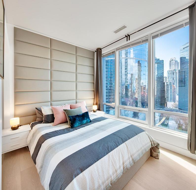 a bedroom with a bed with a large window at City Centre Studio - Best Location! in Vancouver
