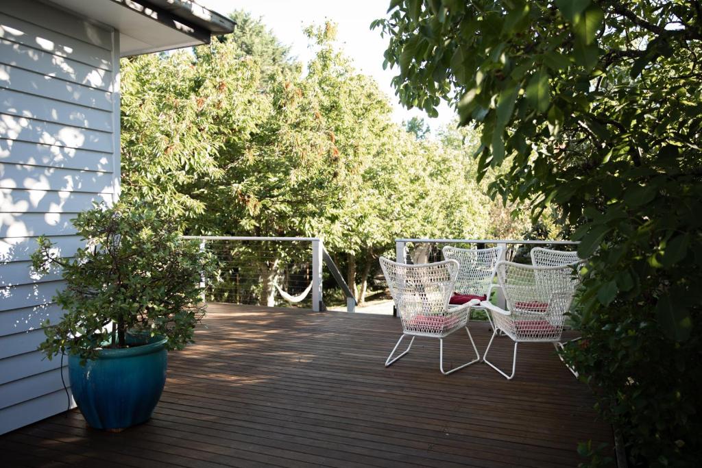 a deck with white chairs and trees on a house at Clara Luce` in Bright