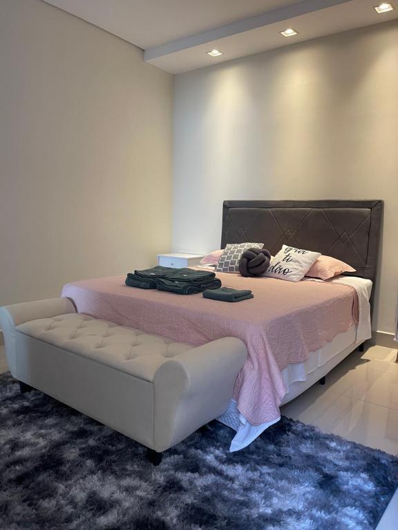 a bedroom with a bed with a couch and a rug at Lilly Queen I in Londrina