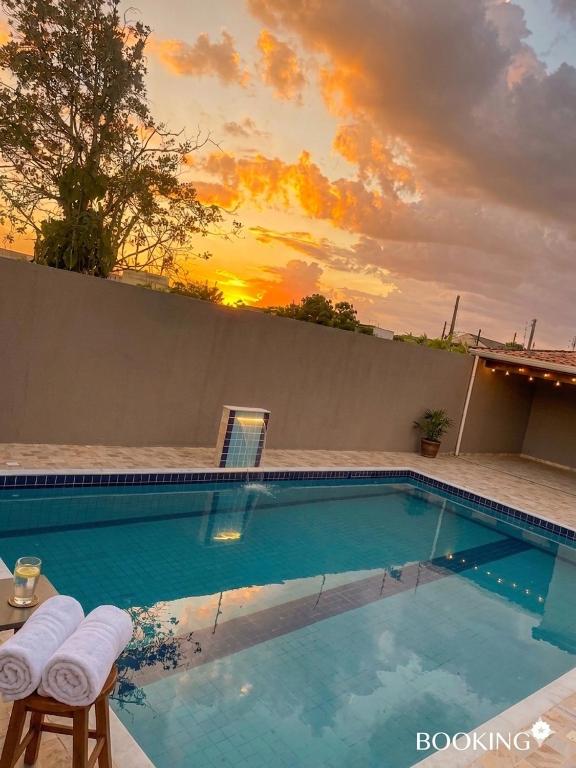 a swimming pool with a sunset in the background at Casa Espaçosa com Piscina, 4 Quartos e Ar-Condicionado in Itanhaém