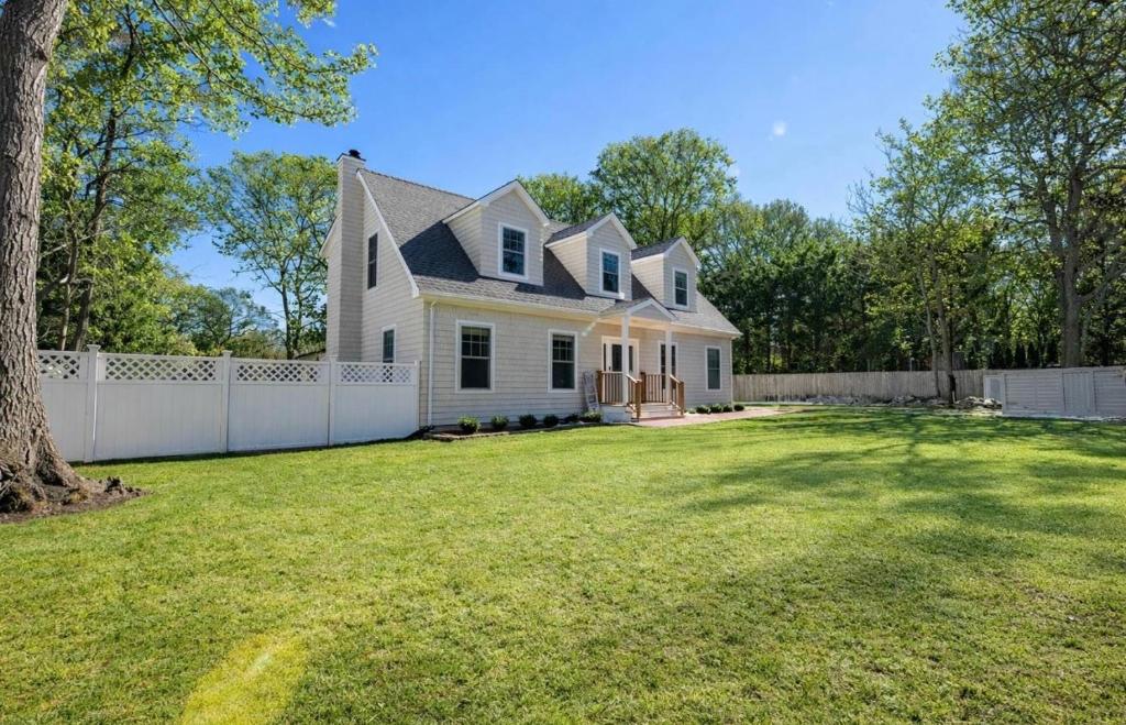 a white house with a fence and a yard at Charming Home for a Perfect Escape in East Hampton