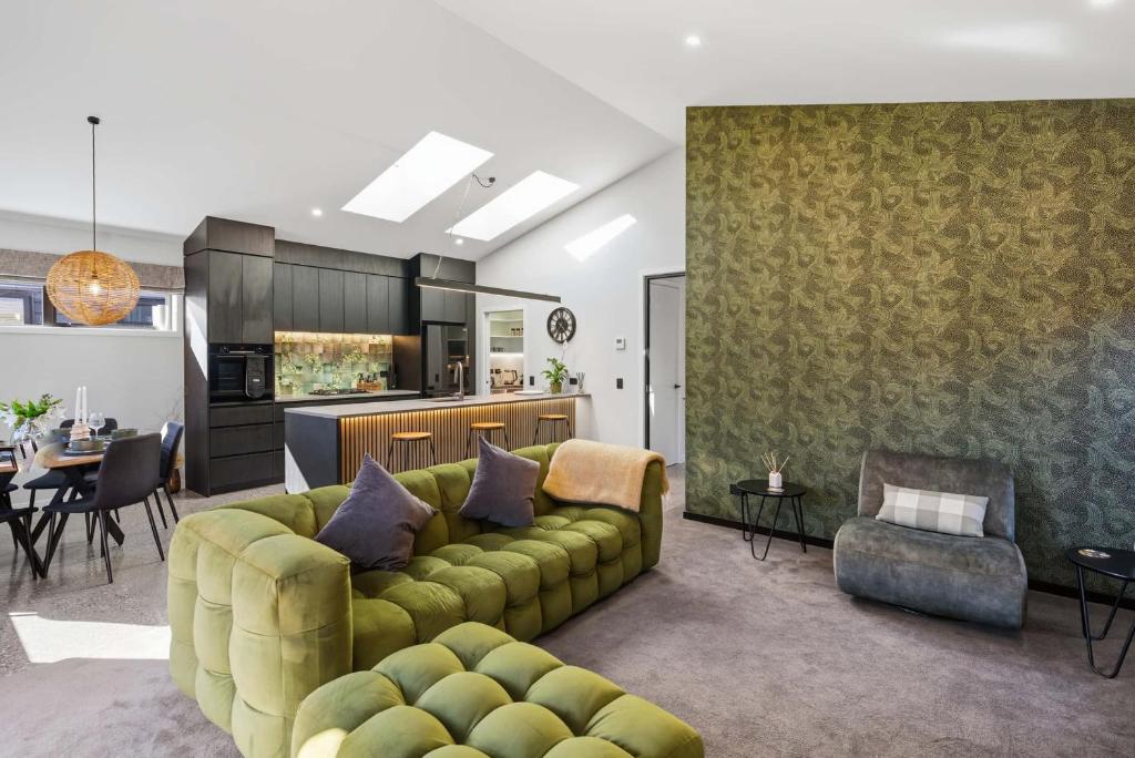 a living room with a green couch and a kitchen at The Reserve on Wooing Tree in Cromwell