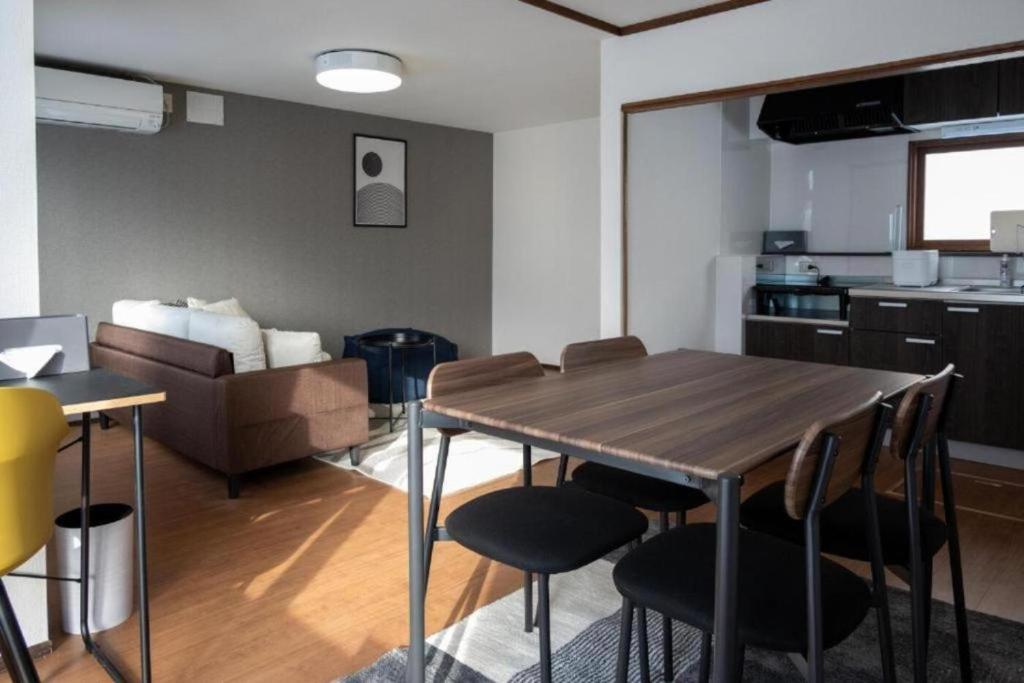 a kitchen and living room with a wooden table and chairs at Biei Relax Stay B in Biei