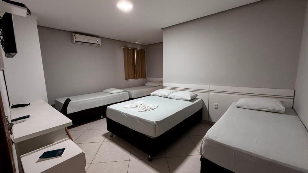 a small room with two beds and a sink at Hotel Estrela de Minas in São Gabriel