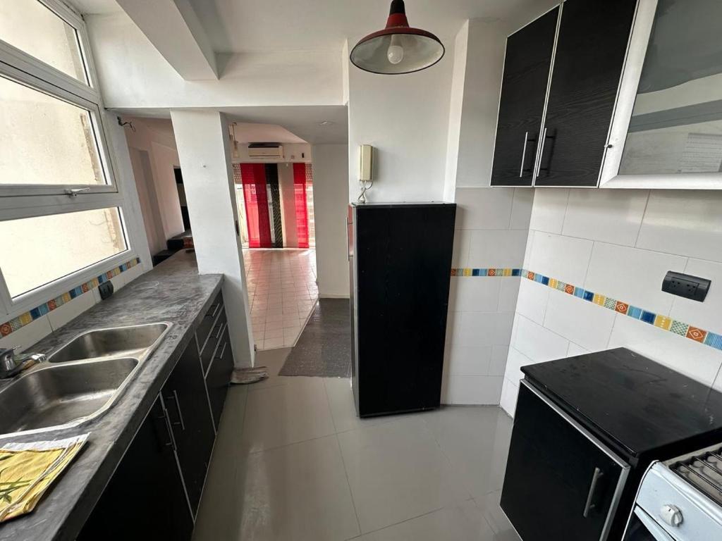 a kitchen with black cabinets and a sink at NM Apartamentos - LANUS OESTE in Villa Sarmiento
