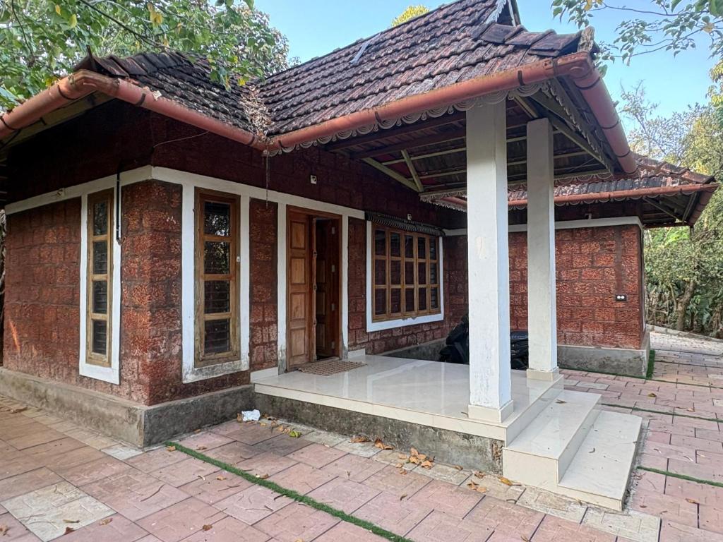a small brick house with a roof at flamingos home stay in Padinjarathara