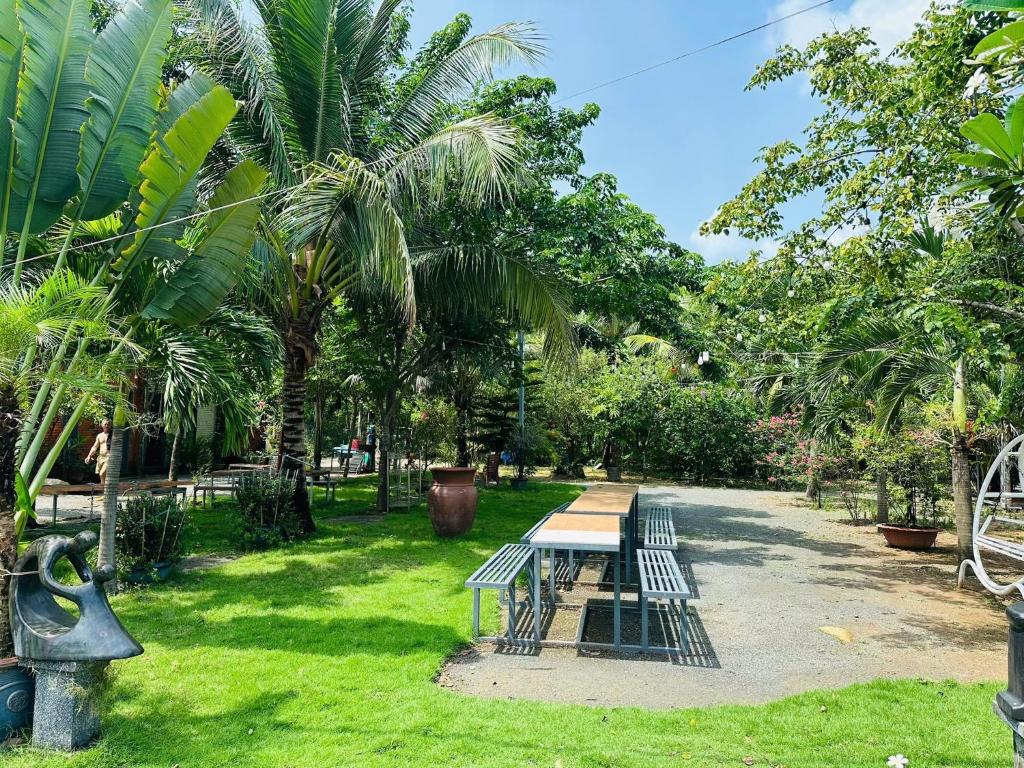 a picnic table and bench in a park with palm trees at Homestay Phố biển cam bình in Lagi