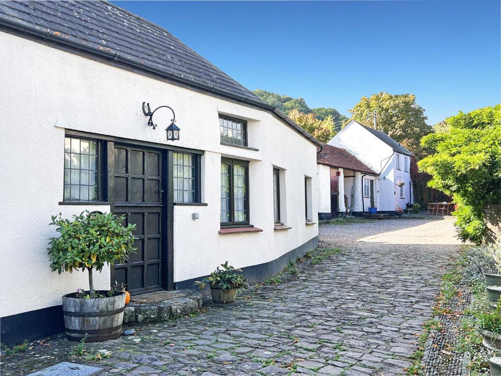 a white house with a cobblestone street at Stables Cottage Ellicombe in Minehead