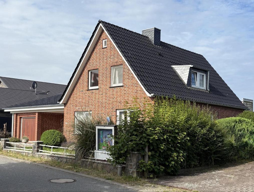 a red brick house with a black roof at Golfhues-Simone-Ferienwohnung-Suedbalkon in Wulfen auf Fehmarn