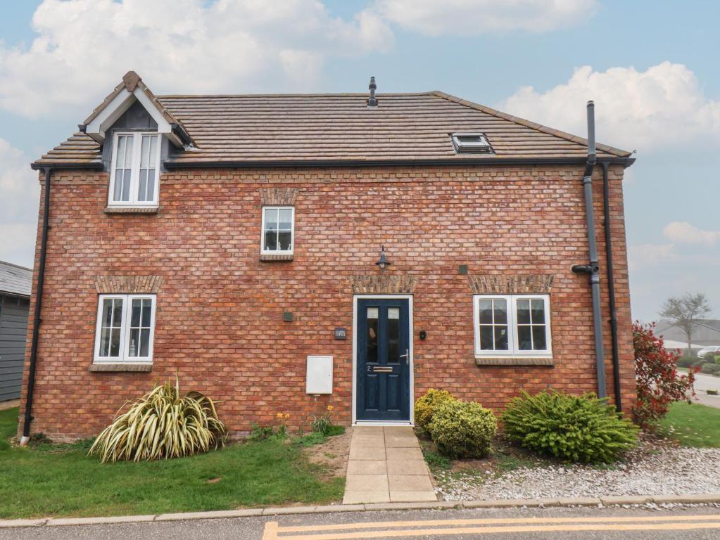 a red brick house with a blue door at Coastal Cottage in Reighton