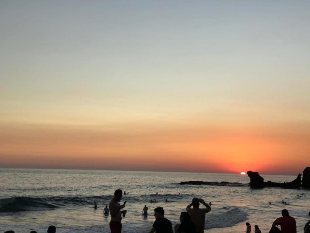 a group of people on the beach at sunset at Islas Boho Tiny Home - Main strip El Tunco in El Sunzal