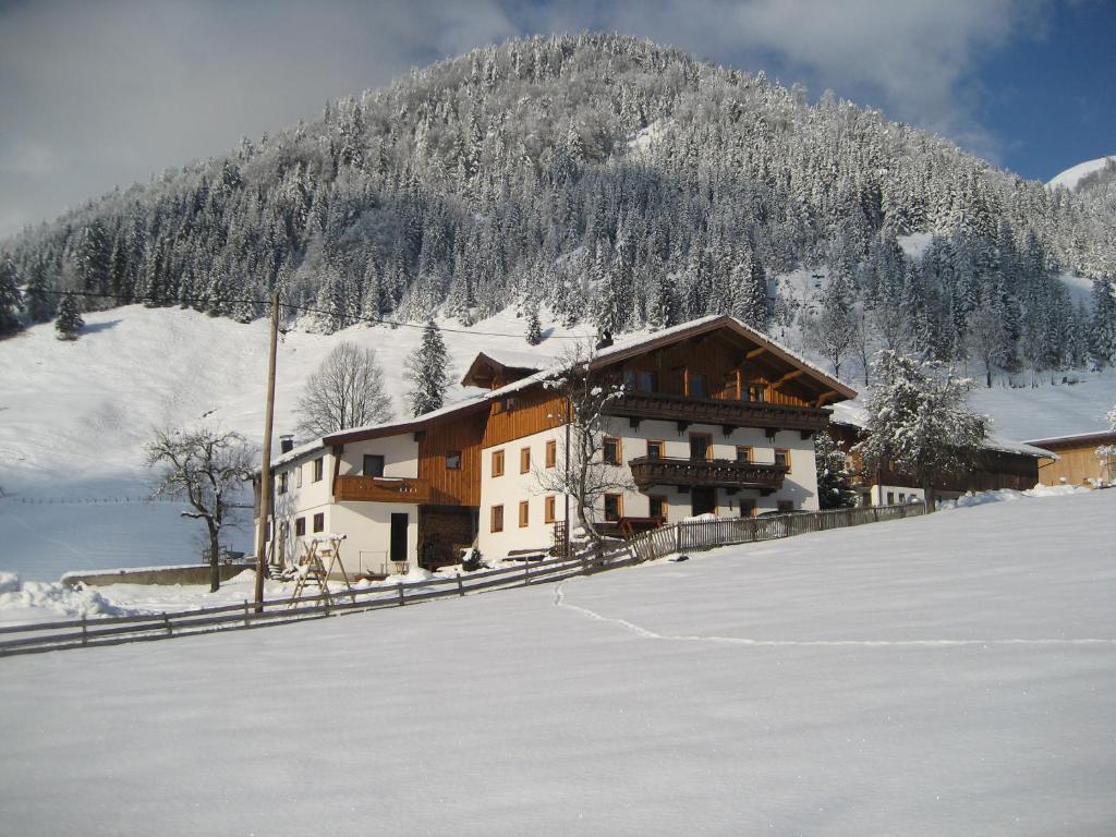 a building in the snow next to a snow covered mountain at Haus Salvenmoser in Walchsee