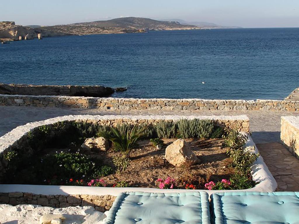 a garden with flowers in a stone planter next to the ocean at Sohoro in Koufonisia