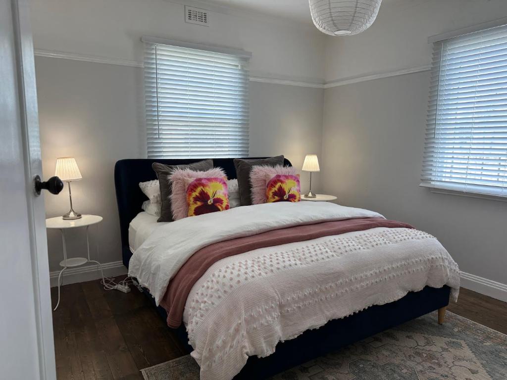 a white bedroom with a large bed with pillows at Daisy Cottage on Duke 3BR in Yarram