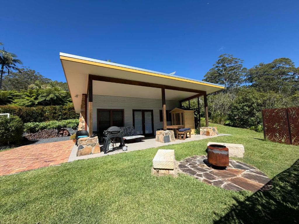 a house with a patio and a grill in a yard at Coffs Coast Mountain Retreat Cabin 1 in Coramba