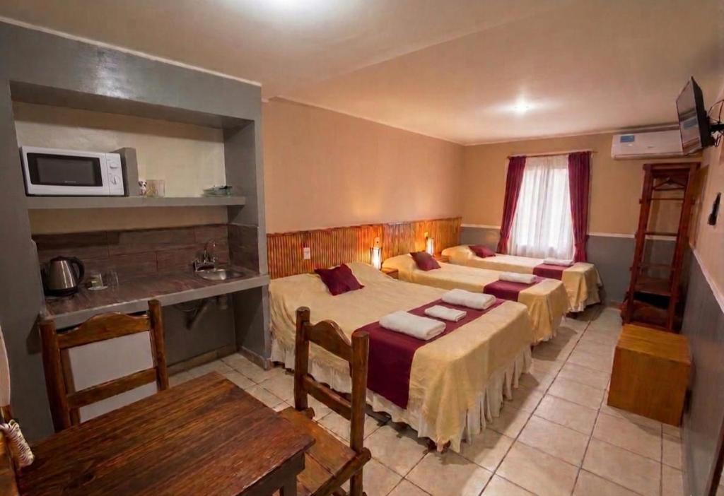 a hotel room with three beds and a microwave at Apart Hotel Belgrano in Perico
