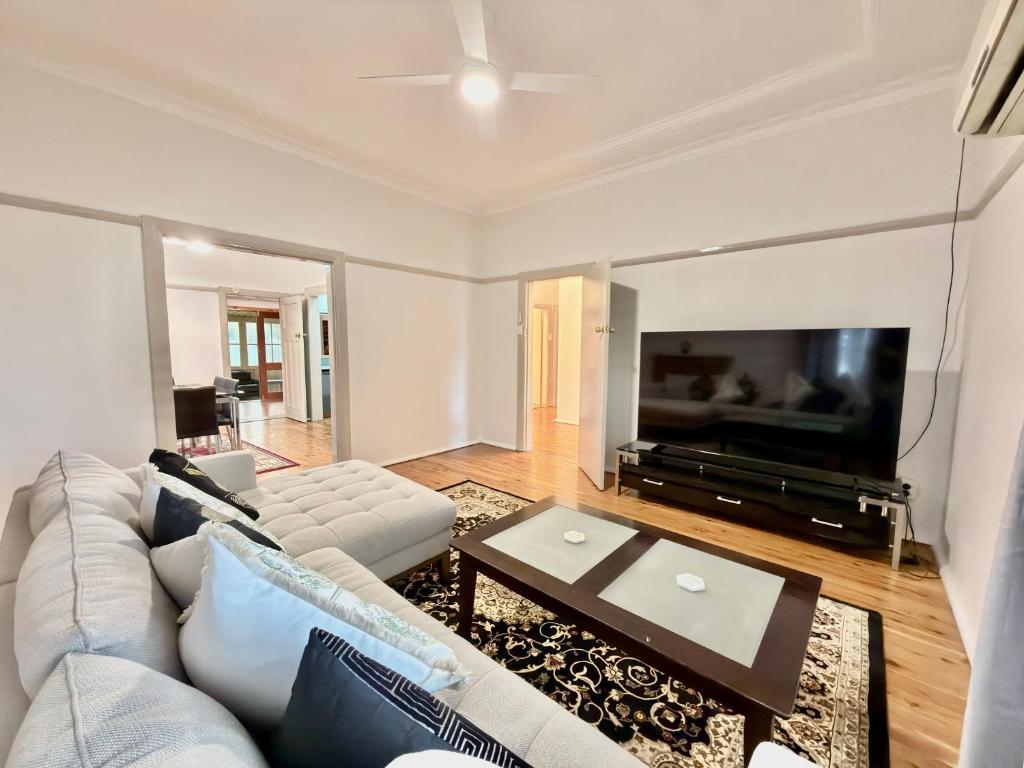 a living room with a white couch and a tv at 72 Cobra Street House in Dubbo