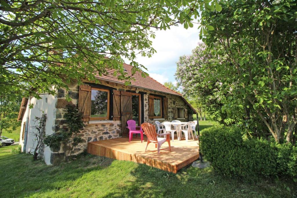 a house with a deck with chairs and a table at Les pierres du mas in La Porcherie