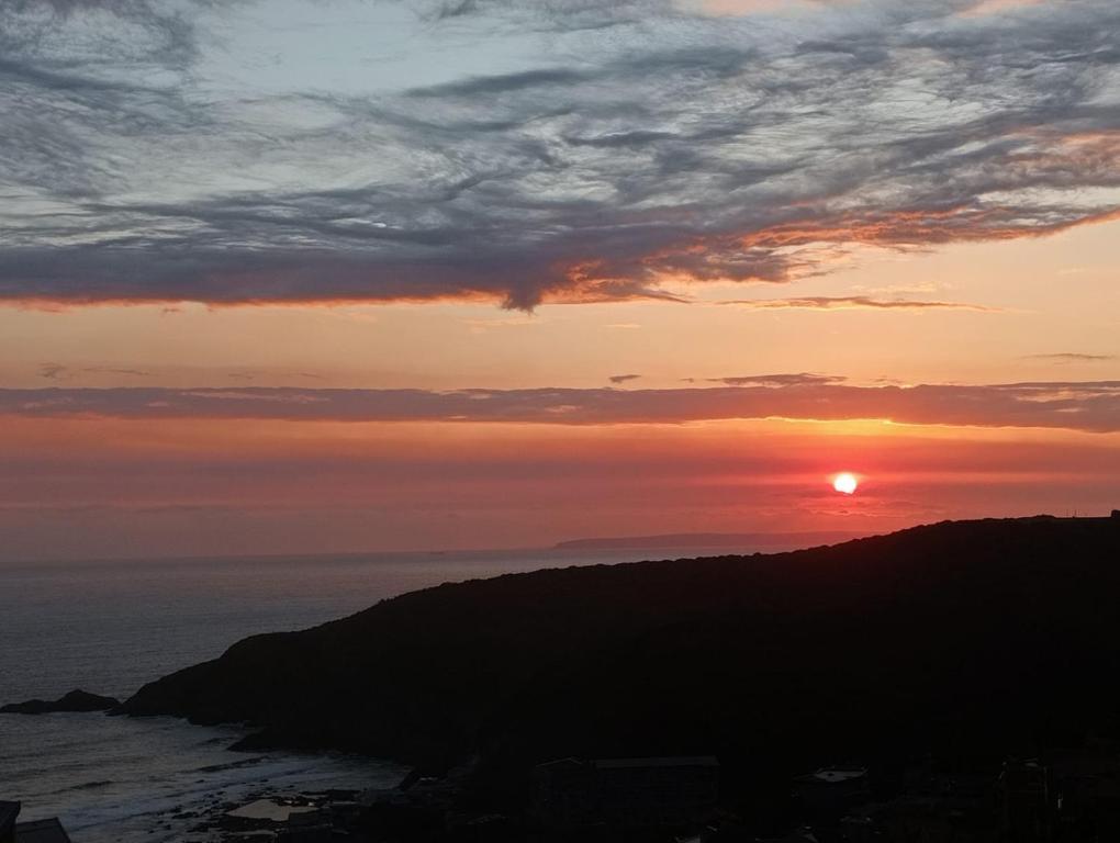 a sunset with the sun setting over the ocean at Fynbos & Foam in Herolds Bay