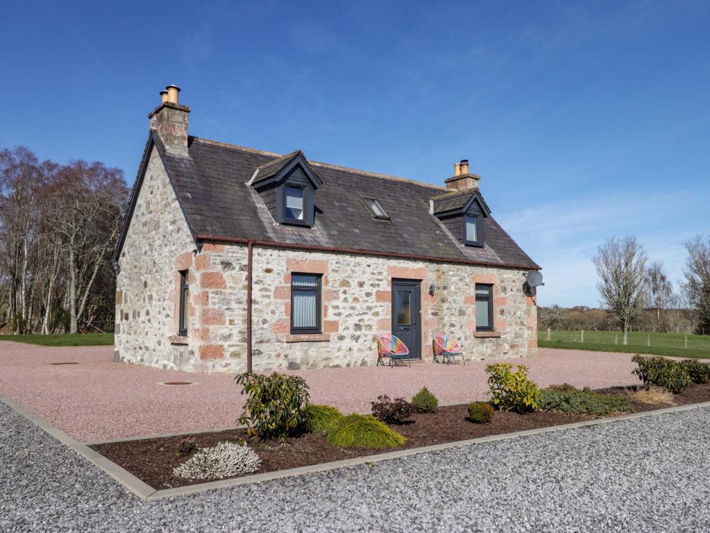 a stone house with a bench in front of it at Nanville in Beauly