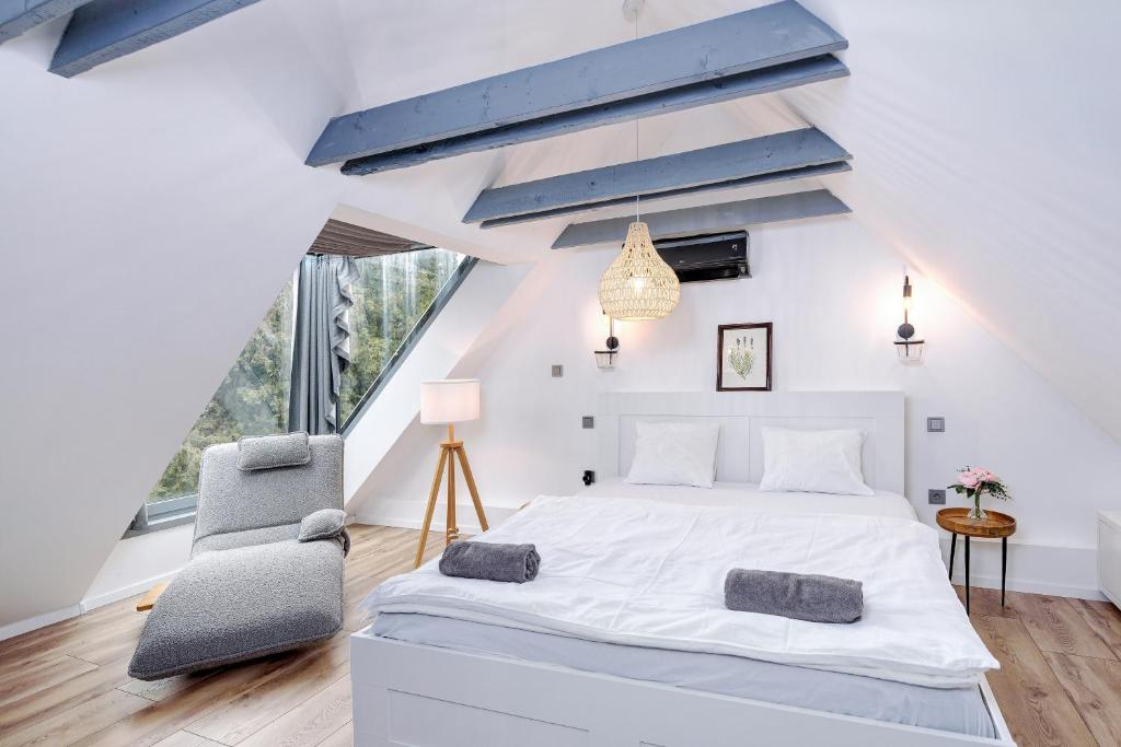 a bedroom with a large white bed and a chair at Káli Kert Vendégház in Szentbékkálla