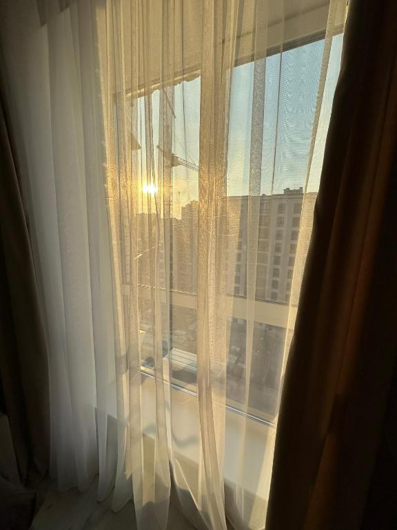 a window with white curtains with a view of a city at ЖК Парус, 10-1 in Chornomorsk