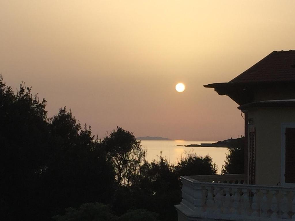 a sunset over a body of water with a house at Hotel Signorini in Castiglioncello