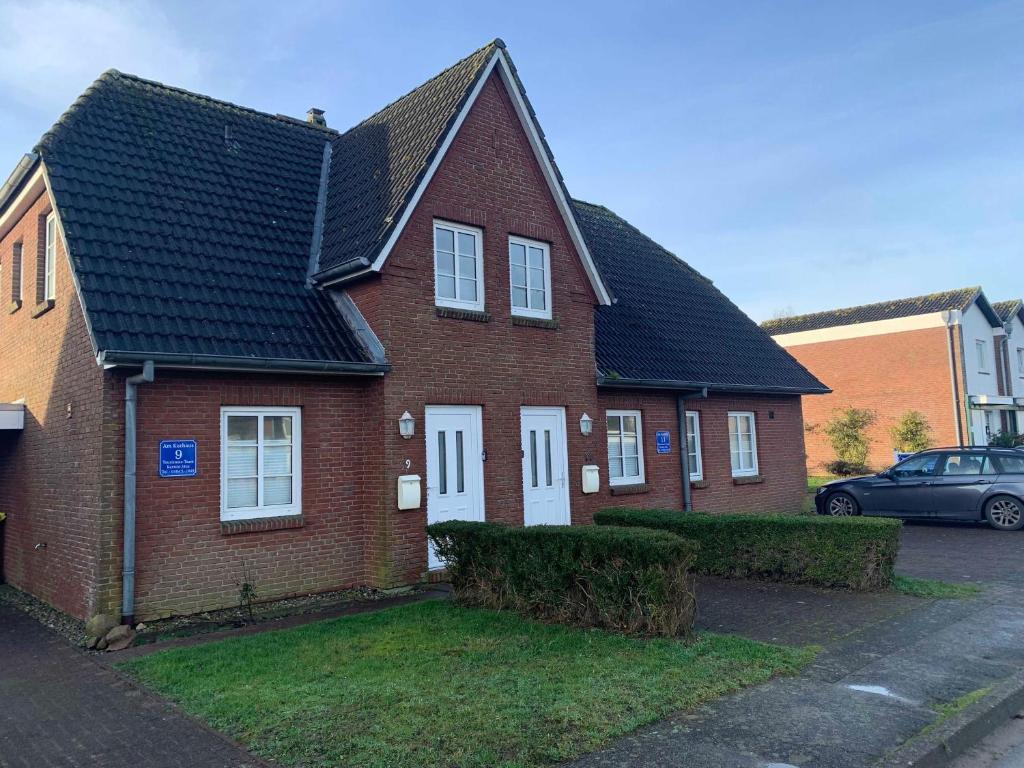 a red brick house with a black roof at Haus am Kurhaus 9 in Nordstrand