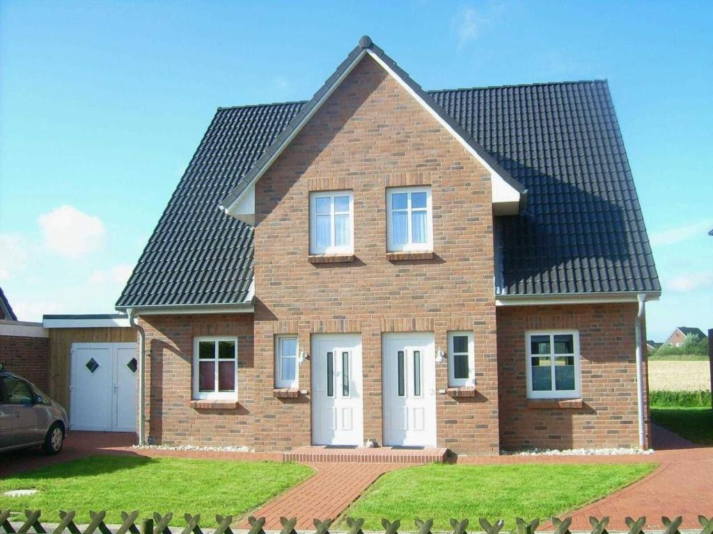a brick house with a black roof at Haus im Halligweg 18 in Nordstrand