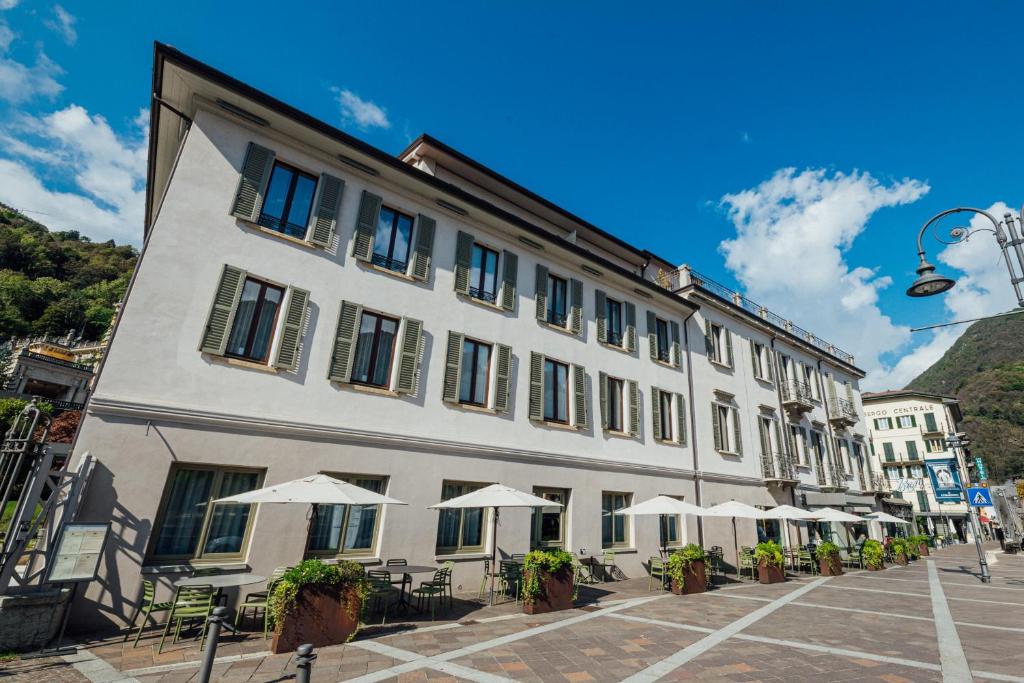 a large white building with tables and umbrellas at Hotel Bigio in San Pellegrino Terme