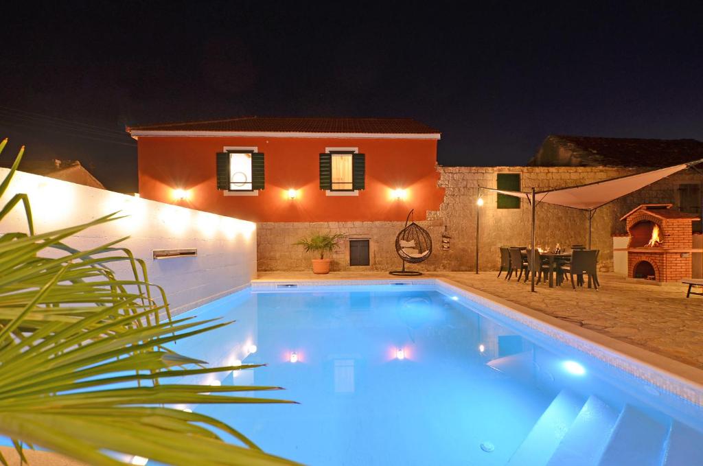 a swimming pool at night with a house in the background at Islander house with pool in Trogir