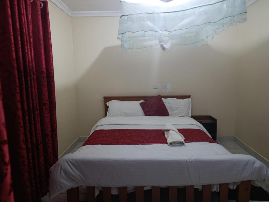 a bedroom with a bed with a red curtain and a window at EasyNest in Kinoo