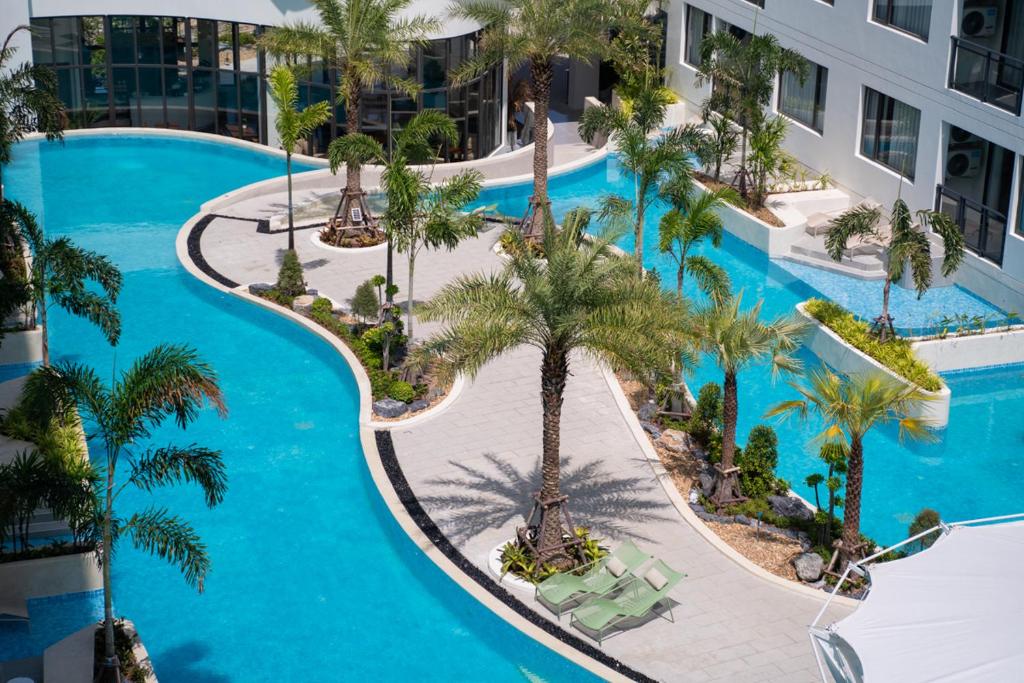 an aerial view of a resort pool with palm trees at Stylish Pool View 1BDR Apartment Bang Tao in Ban Thalat Choeng Thale