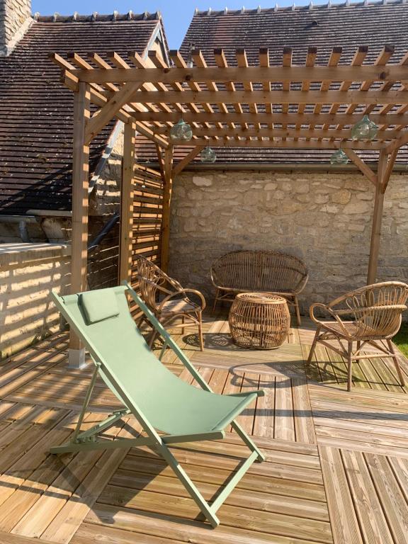 a green chair on a deck with a pergola at Résidence ARTHUS Cinopé in Pierrefonds