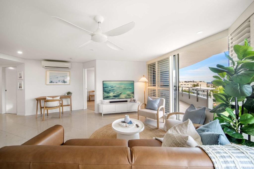 a living room with a couch and a table at Salt & Sky - Stylish Apartment with Pool & Spa in Caloundra