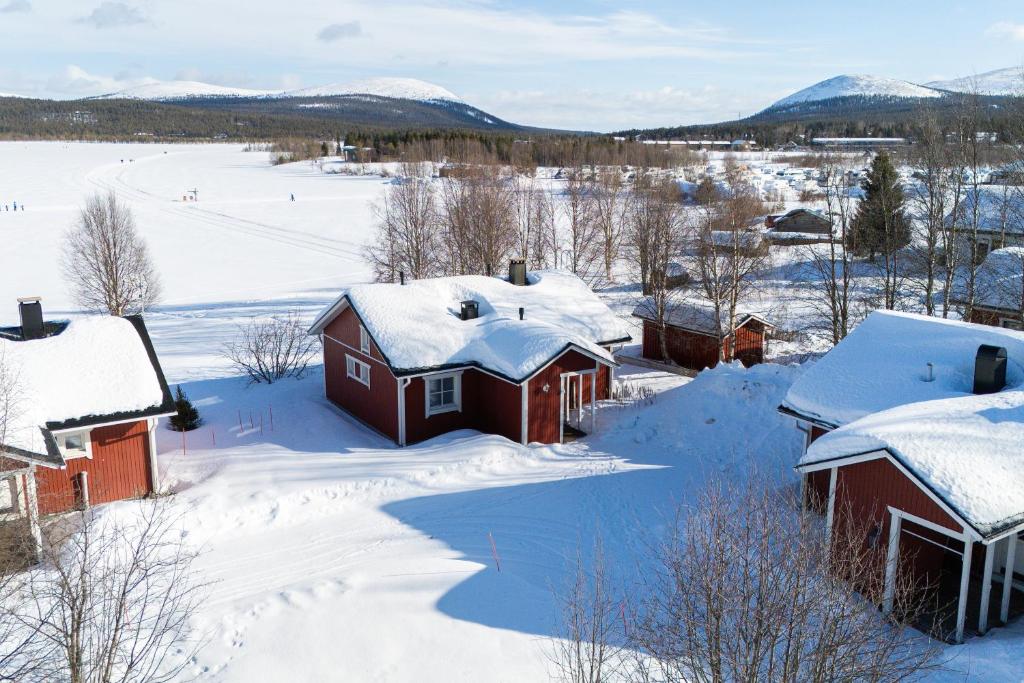 a village covered in snow with mountains in the background at Järven Helmi in Äkäslompolo