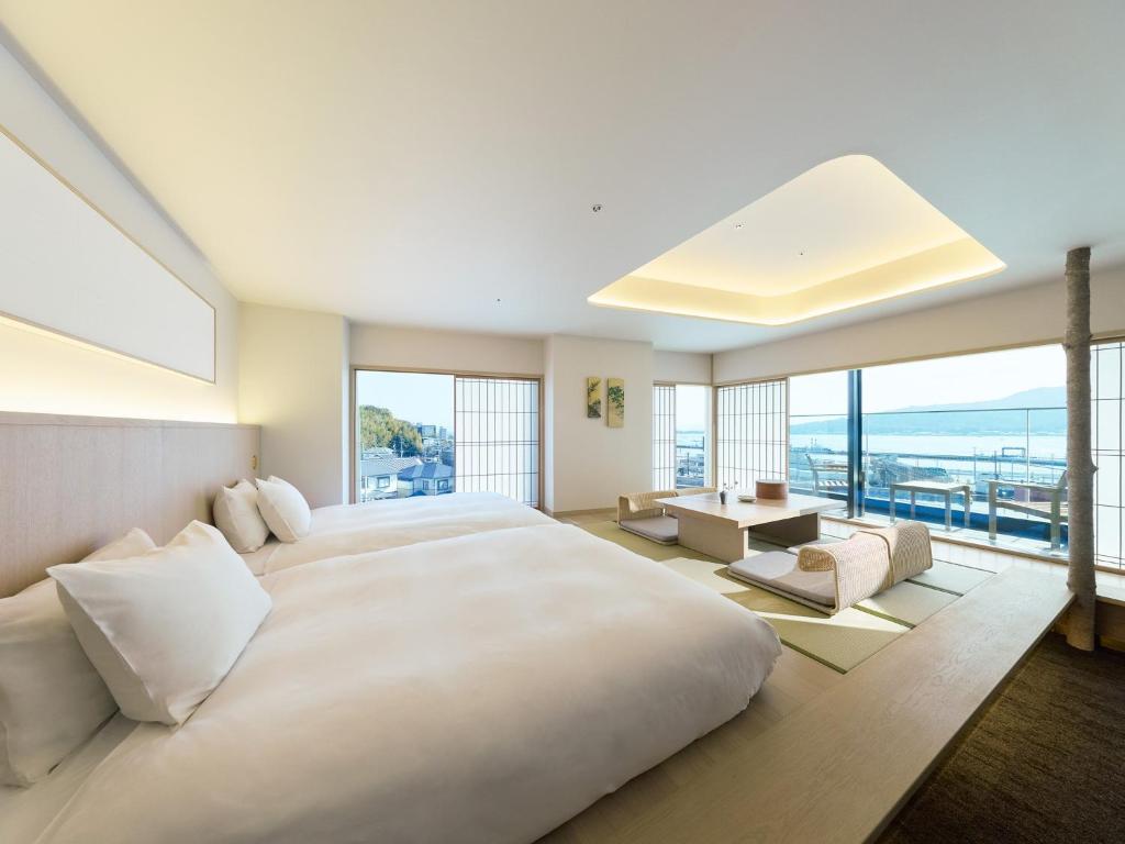 a large white bedroom with a large bed and large windows at HOTEL FORK & KNIFE Miyajima in Miyajima