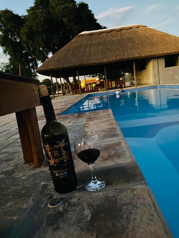a bottle of wine and a glass next to a pool at NAMU Apartments in Katima Mulilo