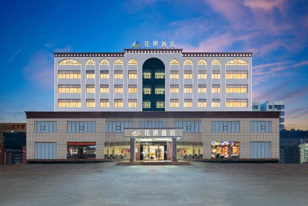 a large building with a lit up facade at 花祺巨幕影院酒店 儋州那大镇夏日广场汽车站店 in Danzhou