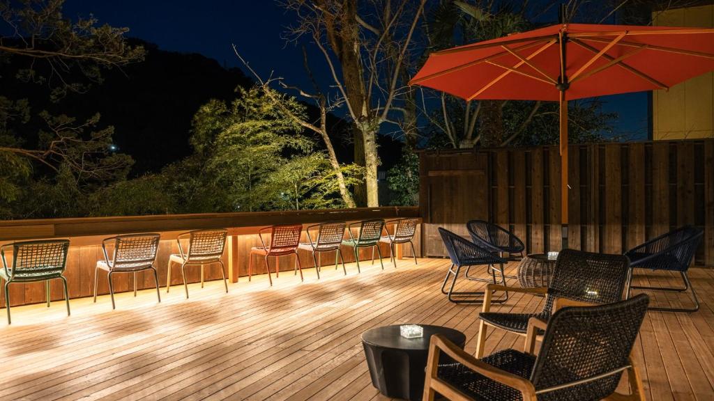 eine Terrasse mit Stühlen, Tischen und einem Sonnenschirm in der Unterkunft HOTEL nehako in Hakone
