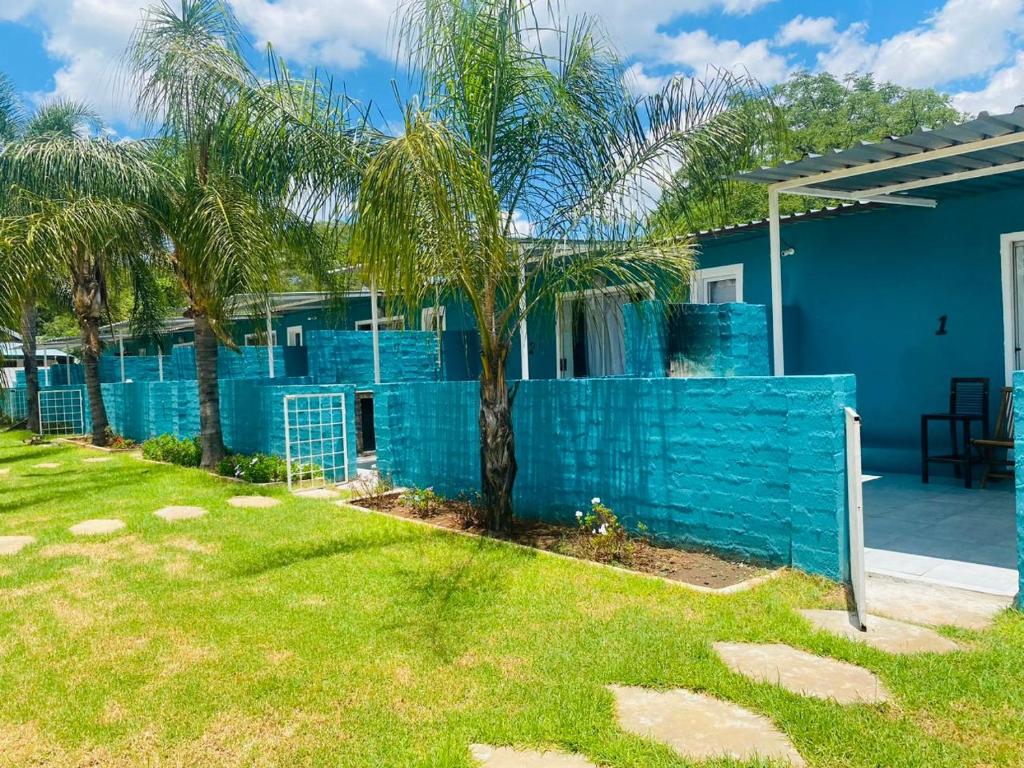 a blue fence in front of a house with palm trees at Alldays Sunset Lodge Wilde Street in Alldays