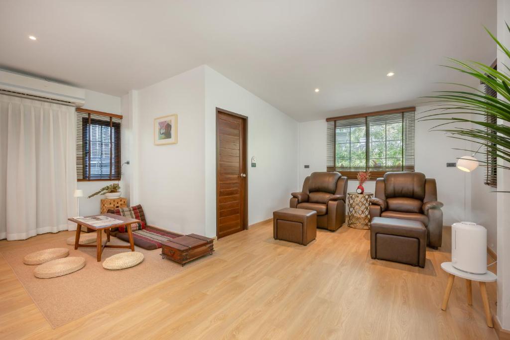 A spacious sitting room with leather armchairs, a low table and a separate curtained seating area.