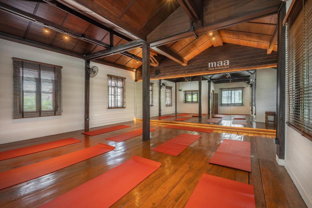 A wood-floored yoga studio with red mats, mirrors and shuttered windows.