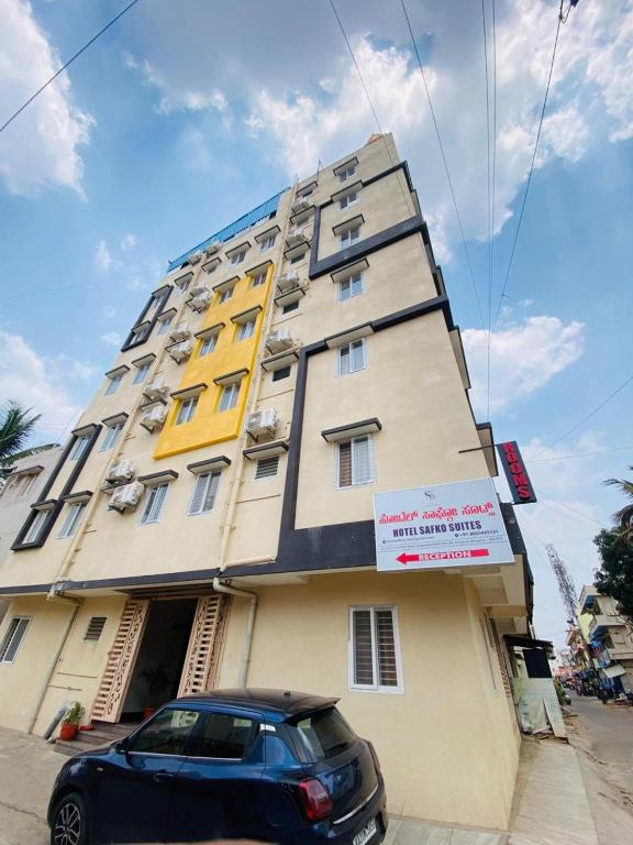 a building with a car parked in front of it at Hotel Safko Suites in Bangalore