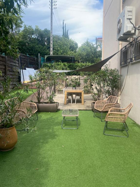 a patio with chairs and a table on green grass at Appartement jardin in Le Cannet